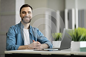 Portrait of freelancer man sitting at desk with laptop computer at office