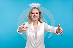 Portrait of friendly angelic woman with halo on her wavy hair welcoming with stretched hands, going to embrace. indoor studio shot