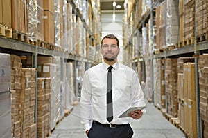 portrait friendly businessman manager in suit working in the warehouse of a company - control of inventories