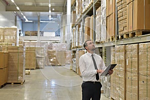 portrait friendly businessman manager in suit working in the warehouse of a company - control of inventories