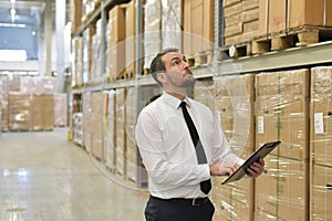 portrait friendly businessman manager in suit working in the warehouse of a company - control of inventories