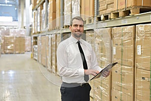 portrait friendly businessman manager in suit working in the warehouse of a company - control of inventories