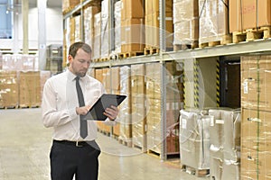 portrait friendly businessman manager in suit working in the warehouse of a company - control of inventories