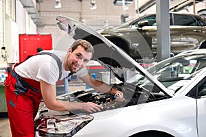 portrait of a friendly car mechanic in the workshop in work clothes - job repair of vehicles