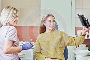 Portrait of friendly doctor and patient girl with tablet at dentist`s office