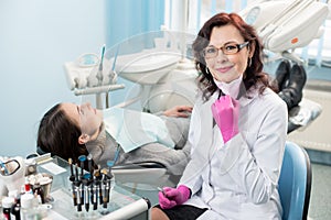 Portrait of friendly female dentist with patient in the chair at the dental office