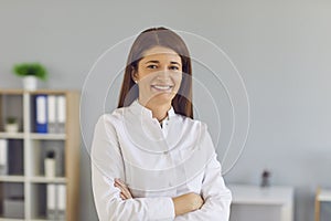 Portrait of a friendly female doctor standing in hospital with folded arms and looking at camera.