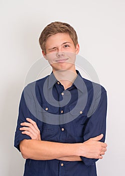 Portrait of friendly funny teenager boy wear blue shirt winking and smiling