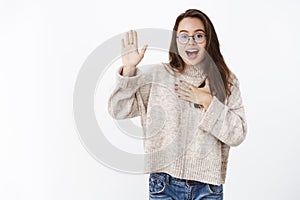 Portrait of friendly-looking relaxed charming carefree woman in glasses making swear or pledge, giving promise with hand