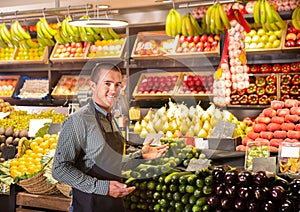 Male shop assistant standing of counter of vegetable shop photo