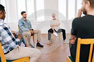 Portrait of friendly mature male mentor corporate leader communicating with multiracial business professional team