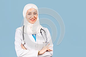 Portrait of a friendly, Muslim doctor or nurse woman in hijab with a stethoscope in a white coat. on a blue background