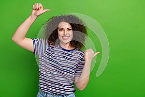 Portrait of friendly pretty girl toothy smile direct thumb fingers empty space isolated on green color background