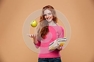 Portrait of a friendly pretty redhead girl holding apple