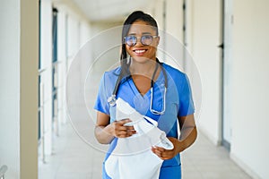 Portrait of friendly, smiling confident female healthcare professional with lab coat, arms crossed holding glasses. Isolated