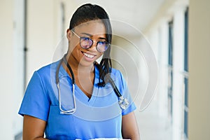 Portrait of friendly, smiling confident female healthcare professional with lab coat, arms crossed holding glasses. Isolated