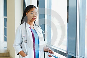 Portrait of friendly, smiling confident female healthcare professional with lab coat, arms crossed holding glasses. Isolated