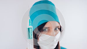 Portrait of a friendly smiling doctor woman or nurse in white medical uniform with a syringe, on white background with co