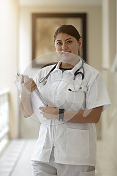 Portrait of friendly, smiling female doctor, healthcare professional wearing lab coat and stethoscope, arms crossed. Latino nurse