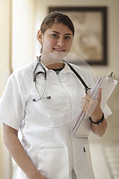 Portrait of friendly, smiling female doctor, healthcare professional wearing lab coat and stethoscope, arms crossed. Latino nurse