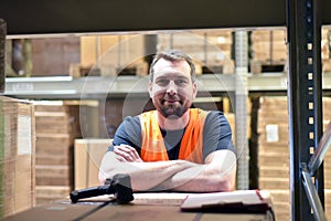 portrait of friendly warehouse worker in a forwarding agency - interior with forklift - transport and storage of goods