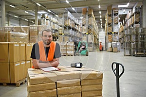 portrait of friendly warehouse worker in a forwarding agency - interior with forklift - transport and storage of goods