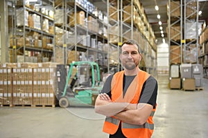 portrait of friendly warehouse worker in a forwarding agency - interior with forklift - transport and storage of goods