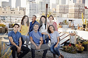 Portrait Of Friends Gathered On Rooftop Terrace For Party With City Skyline In Background