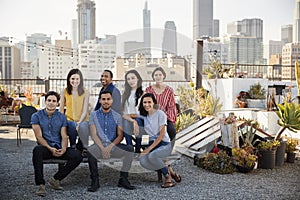 Portrait Of Friends Gathered On Rooftop Terrace For Party With City Skyline In Background