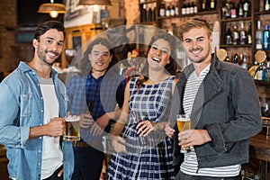 Portrait of friends holding beer glasses and bottles in pub