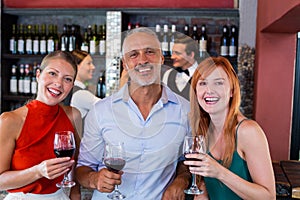 Portrait of friends standing at bar counter with a glass of red wine