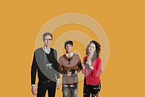 Portrait of friends standing together with cameras over colored background