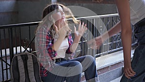 Portrait of frightened Caucasian teenage girl sitting outdoors screaming closing face with hands as unrecognizable bully