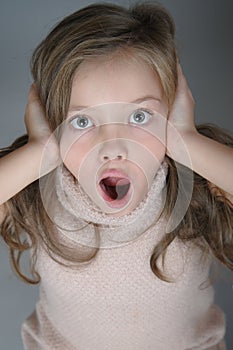 Portrait of a frightened girl who clings to her head and cries.