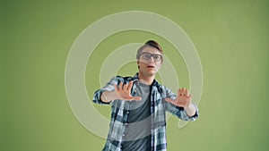 Portrait of frightened hipster looking at camera with fear stretching arms