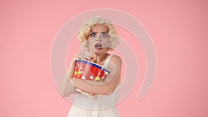 Portrait of frightened woman with big bucket of popcorn. Horror movie. Woman in the image of Marilyn Monroe in studio on