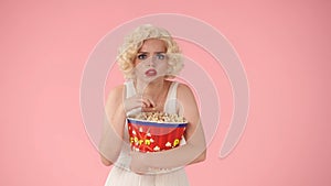 Portrait of frightened woman with big bucket of popcorn. Horror movie. Woman in the image of Marilyn Monroe in studio on