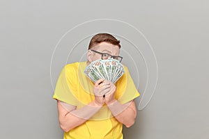 Portrait of frightened worried man covering his face with money