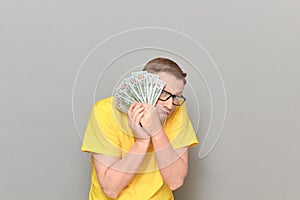 Portrait of frightened worried man covering his face with money