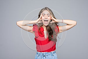 Portrait of a frustrated angry woman screaming out loud and pulling her hair out isolated on the gray background