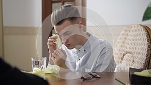 Portrait of frustrated man crying and wiping tears with tissue. Depressed young Caucasian patient on psychological