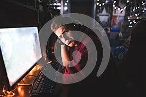 Portrait of a frustrated young man playing video games at home on a computer, looking into a camera with a sad face