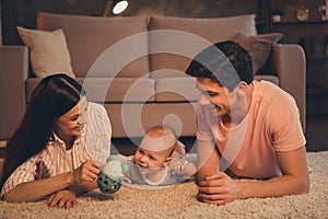 Portrait of full attractive cheerful family parenthood lying on carpet playing with baby having fun at home indoors