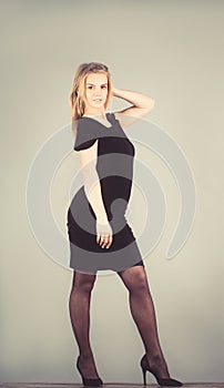 Portrait in full growth of a beautiful young blonde woman in sexy black dress, isolated on gray background.