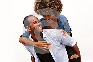 Fun couple smiling in embrace by white wall