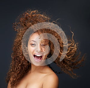 Portrait of a fun and happy young woman laughing with hair blowing