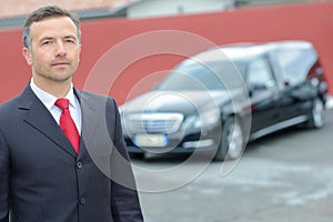 Portrait funeral director standing in front hearse