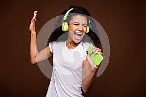 Portrait of funky afro american youth imagine she perform rock concert sing song use smartphone mic listen music on