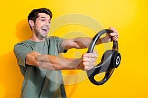 Portrait of funky ecstatic guy with stubble holding steering wheel buy new car look empty space isolated on yellow color