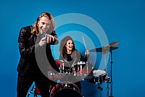 Portrait of funky famous rock band youth team two people man point index finger sing song mic woman play drums enjoy